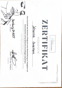 10 Ein Zertifikat in deutscher Sprache mit dem Titel „Zertifikat Visagistik“, ausgestellt auf Johanna Grossmann, mit Unterschriften, einem Logo und einer Abbildung einer Frau, die sich links schminkt, als Nachweis ihrer erfolgreichen professionellen Kosmetikausbildung.