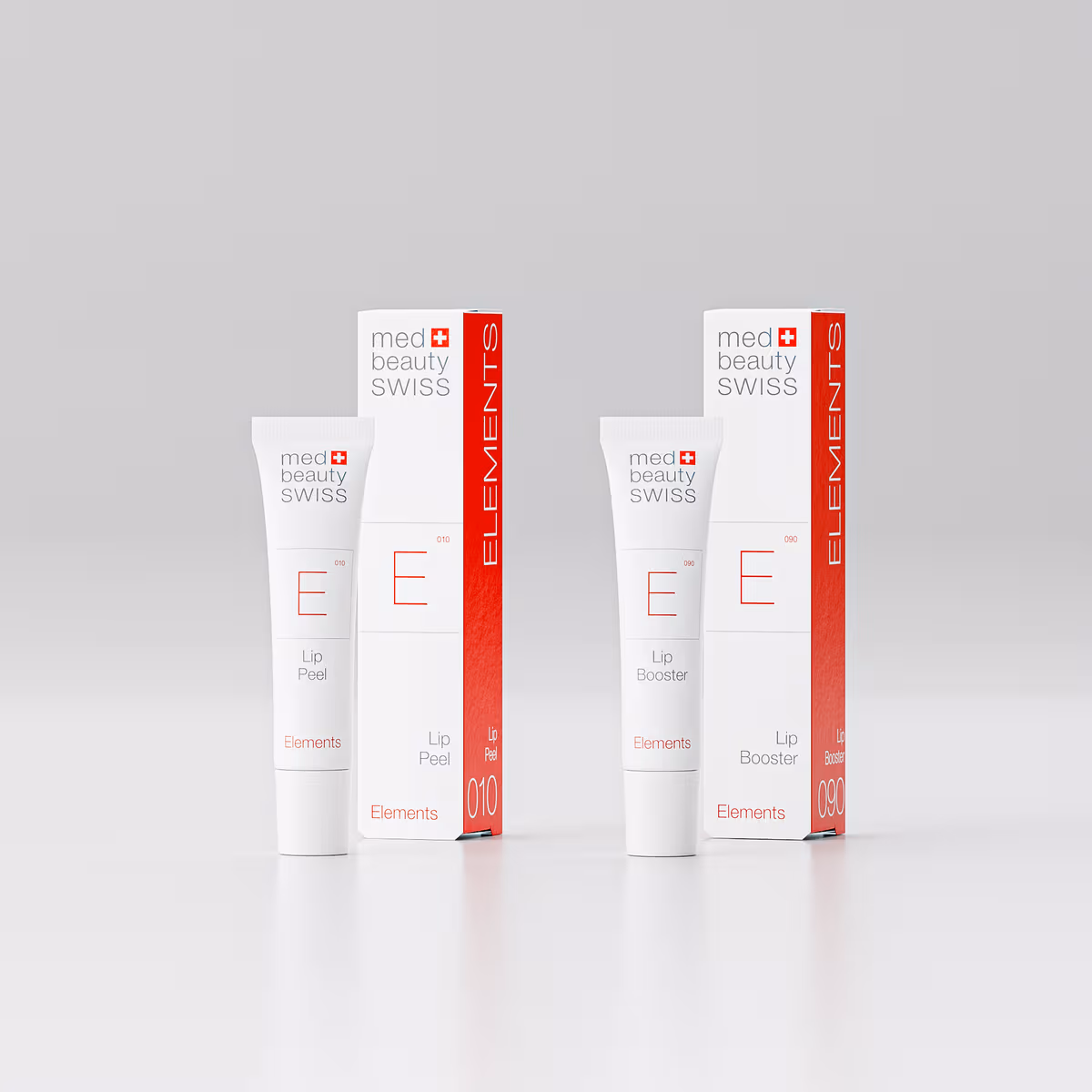 Lip2BBooster_V2 Zwei weiße und rote „med beauty SWISS“-Hautpflegeprodukte mit ihren Verpackungen, beschriftet mit „Lip Peel“ und „Lip Booster“, sind aufrecht auf einem schlichten, hellen Hintergrund abgebildet. Auf den Verpackungen steht seitlich vertikal „ELEMENTS“ – eine perfekte Ergänzung für alle, die eine Kosmetikerin-Ausbildung absolvieren oder hochwertige Behandlungen in einer Kosmetikpraxis in Einbeck suchen.
